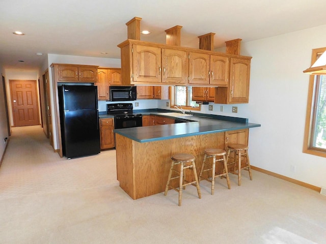 kitchen with light carpet, kitchen peninsula, sink, black appliances, and a kitchen bar