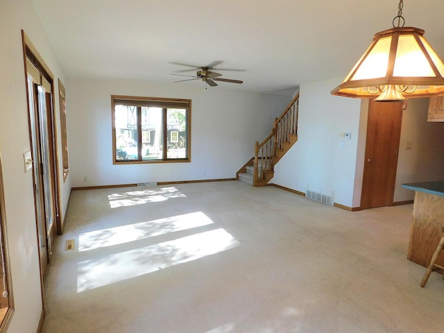 unfurnished living room featuring light carpet and ceiling fan