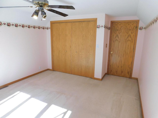 unfurnished bedroom featuring a closet, ceiling fan, lofted ceiling, and light colored carpet