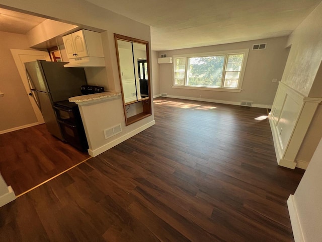 kitchen with dark wood-type flooring, white cabinets, and stainless steel refrigerator