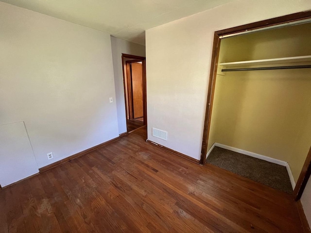 unfurnished bedroom with dark hardwood / wood-style flooring and a closet