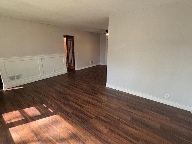 empty room with dark hardwood / wood-style floors, ceiling fan, and a barn door