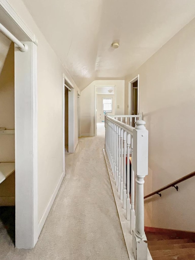 corridor featuring light carpet and vaulted ceiling