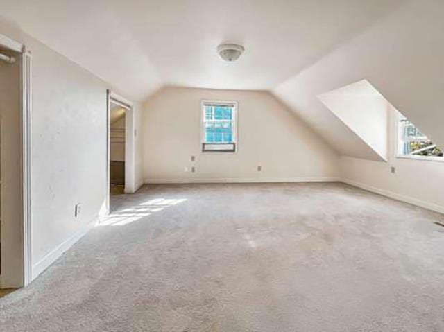 additional living space with vaulted ceiling and light carpet