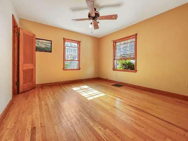 unfurnished room with ceiling fan, light wood-type flooring, and plenty of natural light