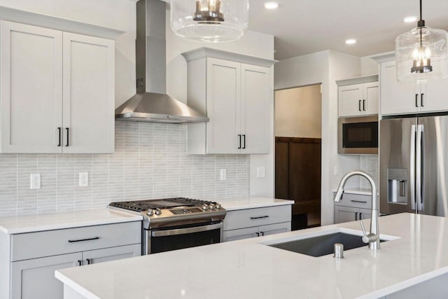 kitchen featuring pendant lighting, a kitchen island with sink, wall chimney range hood, decorative backsplash, and appliances with stainless steel finishes