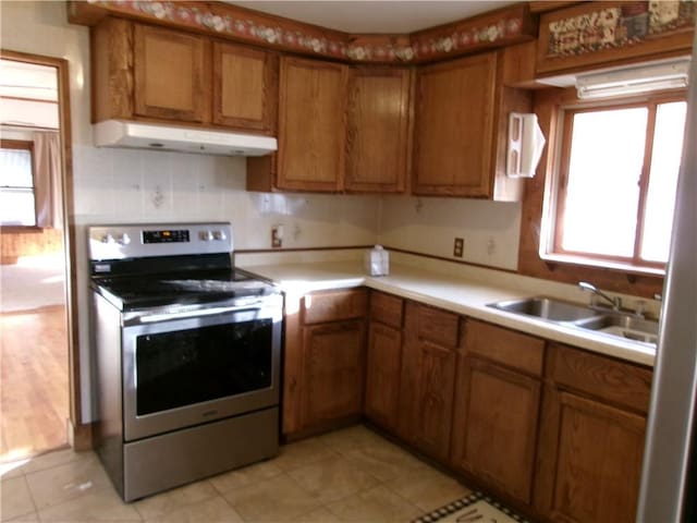 kitchen featuring decorative backsplash, light tile patterned floors, sink, and stainless steel electric range oven