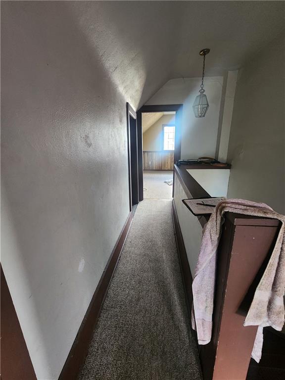 hallway with vaulted ceiling and carpet flooring