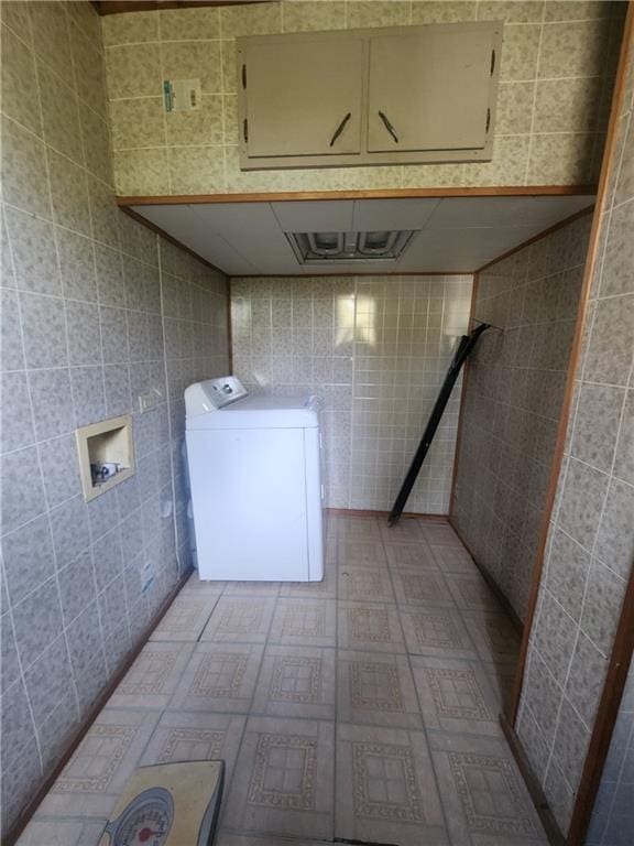 clothes washing area with washer / clothes dryer, cabinets, and tile walls