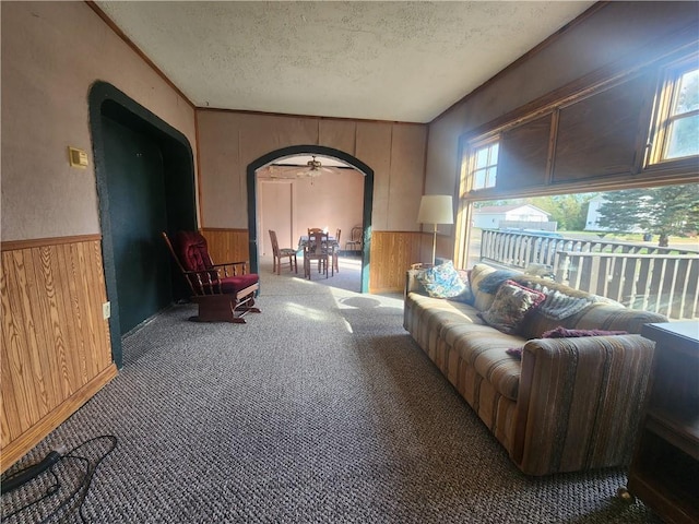 sitting room with a textured ceiling, wood walls, and ceiling fan