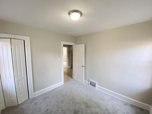 unfurnished bedroom with light carpet and a closet