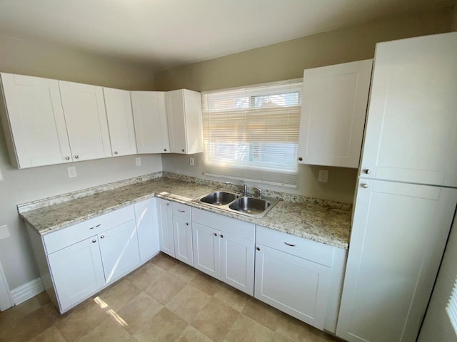 kitchen featuring light stone countertops, sink, and white cabinetry