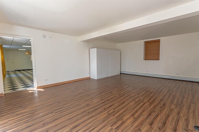 empty room with baseboard heating and dark wood-type flooring