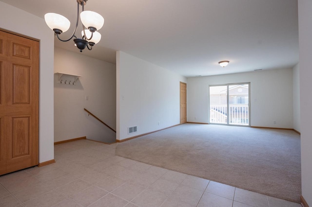 carpeted empty room featuring a chandelier