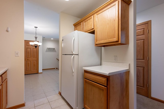 kitchen with white fridge, light tile patterned flooring, decorative light fixtures, a notable chandelier, and light brown cabinets