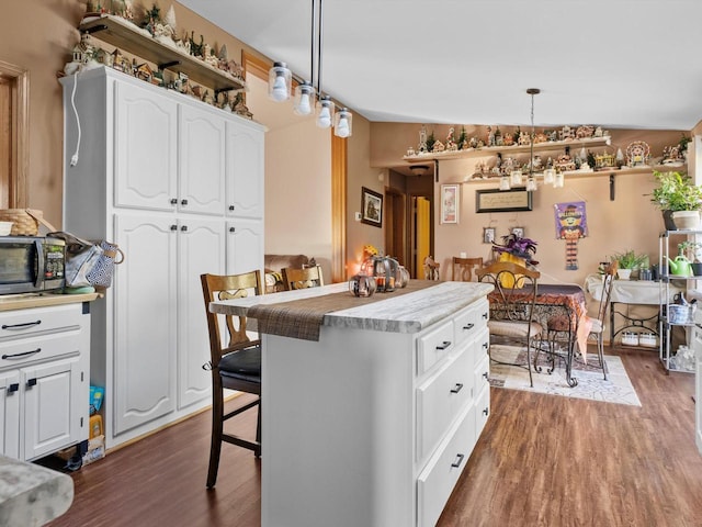 kitchen featuring a kitchen breakfast bar, hanging light fixtures, lofted ceiling, and white cabinets