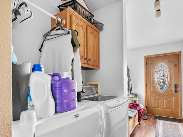 laundry area featuring cabinets, hardwood / wood-style floors, and washing machine and clothes dryer