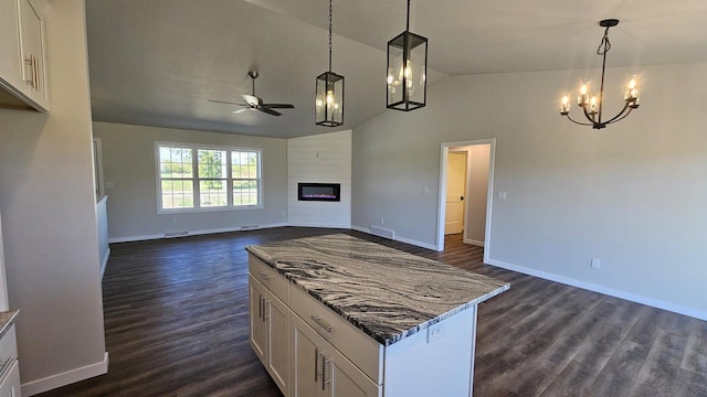 kitchen with lofted ceiling, white cabinetry, dark stone countertops, and pendant lighting