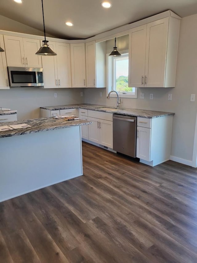 kitchen with appliances with stainless steel finishes, white cabinetry, dark hardwood / wood-style flooring, decorative light fixtures, and sink