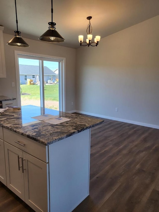 kitchen featuring dark stone counters, hanging light fixtures, dark wood-type flooring, and white cabinets