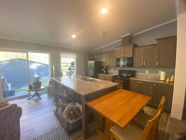 kitchen featuring black appliances, lofted ceiling, a kitchen island with sink, and plenty of natural light