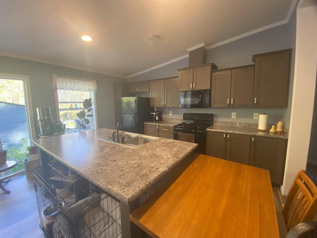 kitchen with sink, a center island with sink, black appliances, a kitchen breakfast bar, and vaulted ceiling