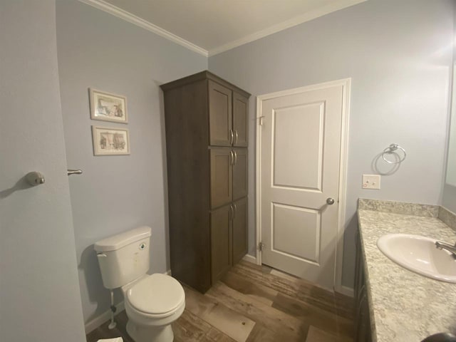 bathroom featuring ornamental molding, vanity, hardwood / wood-style floors, and toilet