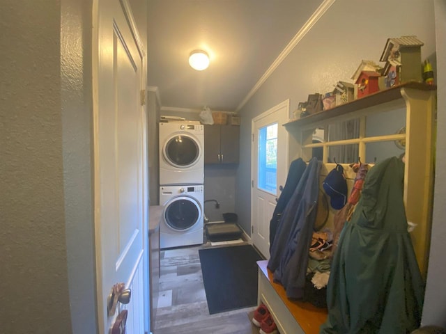 washroom featuring stacked washer / drying machine, crown molding, cabinets, and hardwood / wood-style flooring