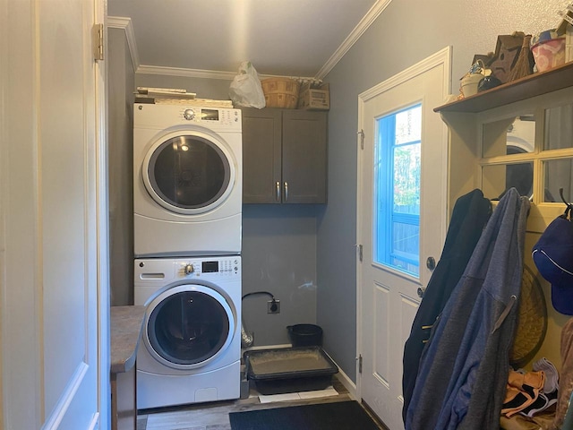 clothes washing area with cabinets, stacked washer / dryer, ornamental molding, and dark hardwood / wood-style flooring