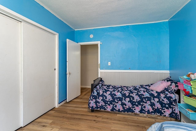 bedroom featuring a textured ceiling, wood-type flooring, and crown molding