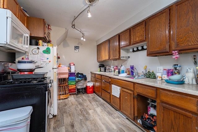 kitchen featuring gas stove, light hardwood / wood-style floors, track lighting, and sink