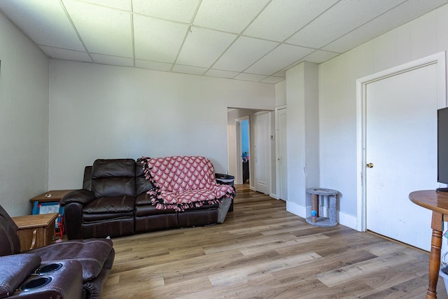 living room with a paneled ceiling and light hardwood / wood-style floors