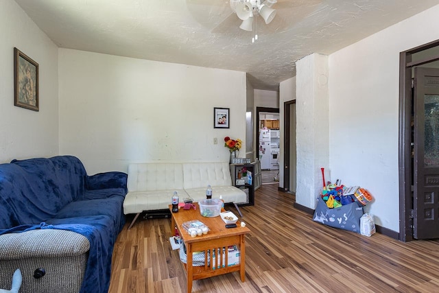 living room featuring wood-type flooring, a textured ceiling, and ceiling fan