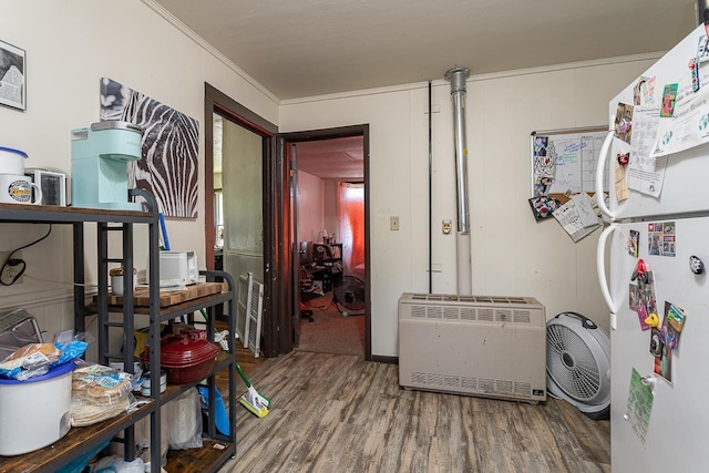 clothes washing area featuring ornamental molding, wood-type flooring, and heating unit