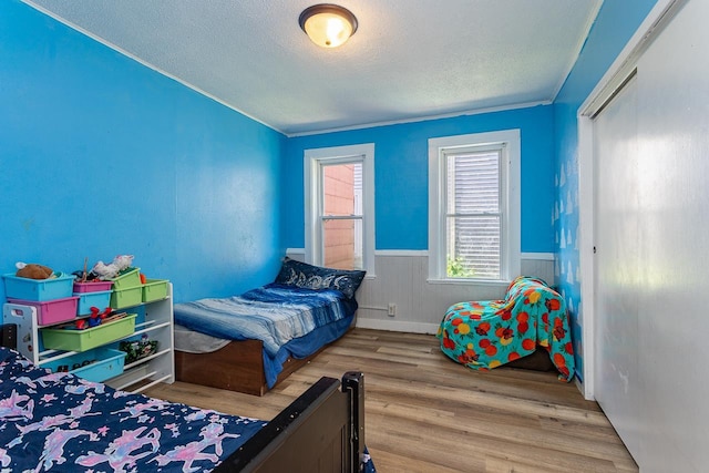 bedroom featuring a textured ceiling, ornamental molding, and hardwood / wood-style floors