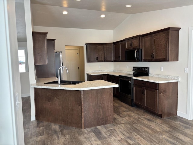 kitchen with sink, dark brown cabinets, dark hardwood / wood-style floors, black appliances, and kitchen peninsula