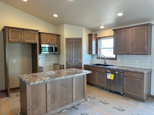 kitchen featuring tasteful backsplash, lofted ceiling, sink, a center island, and stainless steel appliances