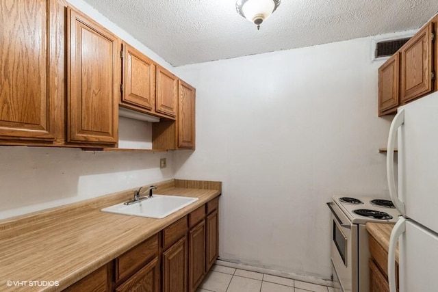 kitchen featuring white appliances, a textured ceiling, light tile patterned floors, and sink