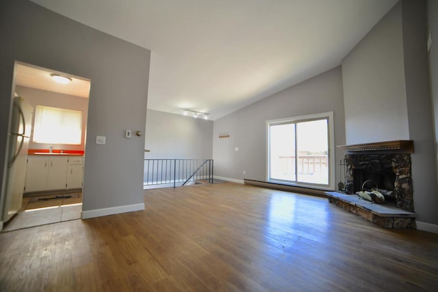 unfurnished living room with hardwood / wood-style flooring, a fireplace, sink, and high vaulted ceiling