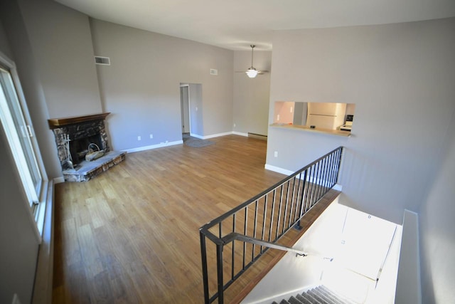 interior space featuring ceiling fan, hardwood / wood-style flooring, a fireplace, and high vaulted ceiling