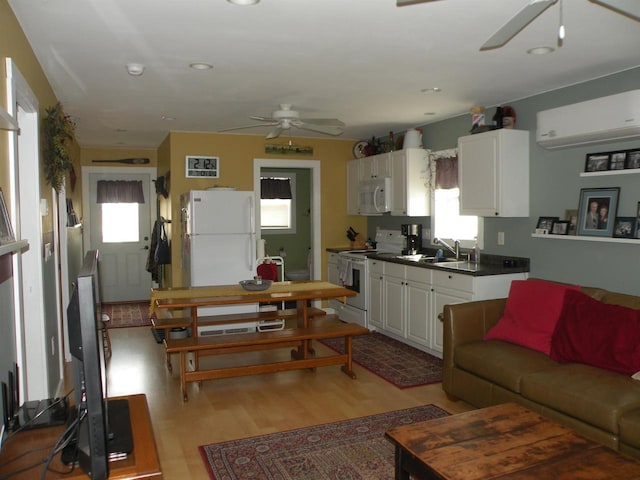 kitchen featuring light wood-type flooring, white appliances, white cabinetry, and a healthy amount of sunlight