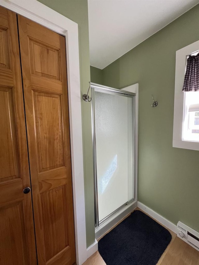 bathroom with walk in shower, hardwood / wood-style floors, and a baseboard radiator