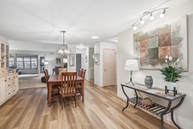 dining area with light hardwood / wood-style flooring and a chandelier