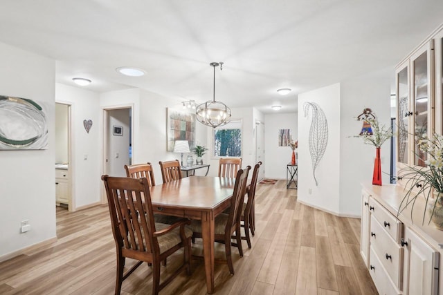 dining room with light hardwood / wood-style floors and a notable chandelier