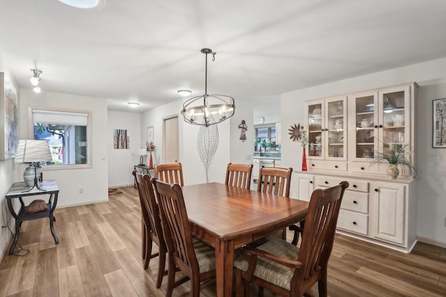 dining space featuring light hardwood / wood-style flooring, an inviting chandelier, and plenty of natural light