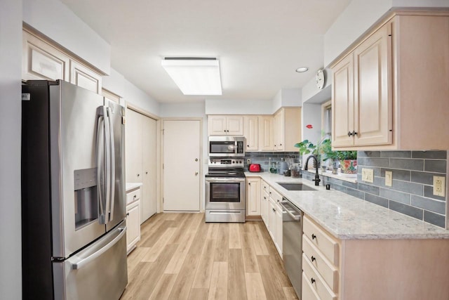 kitchen with light brown cabinets, decorative backsplash, appliances with stainless steel finishes, light hardwood / wood-style floors, and sink