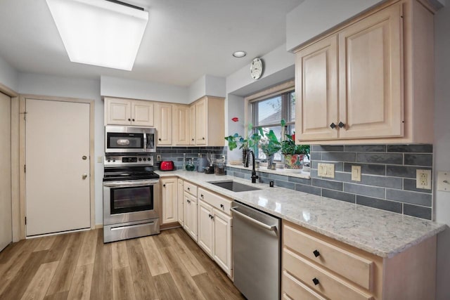 kitchen with light brown cabinets, stainless steel appliances, sink, and light wood-type flooring