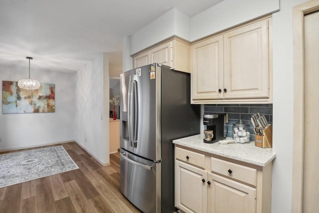 kitchen featuring hardwood / wood-style floors, cream cabinets, backsplash, stainless steel refrigerator with ice dispenser, and decorative light fixtures