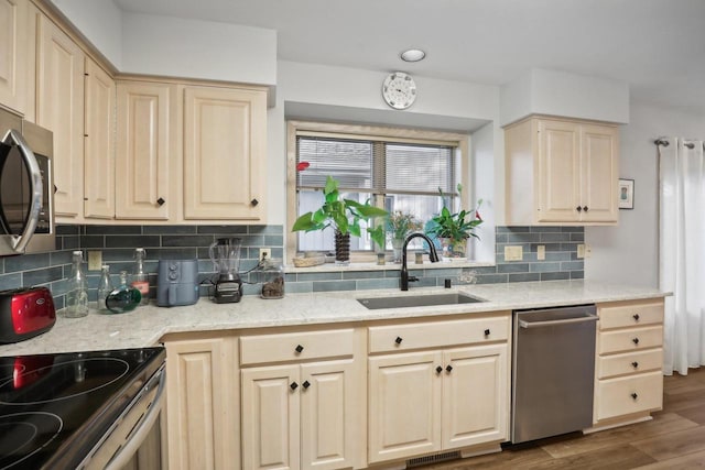 kitchen with dark wood-type flooring, stainless steel appliances, sink, light stone countertops, and tasteful backsplash