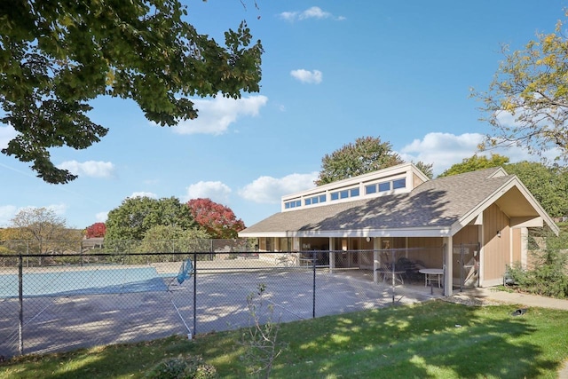 rear view of house with a patio area, a covered pool, and a lawn